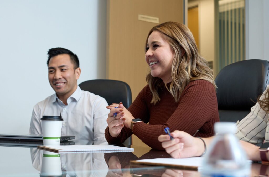 A smiling woman and man sitting at a meeting room table