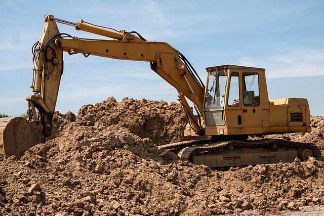 Yellow excavator moving dirt at construction site.