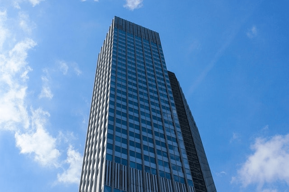 Skyscraper against blue sky with clouds.