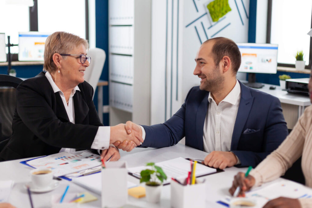 Two professionals shaking hands in office meeting.