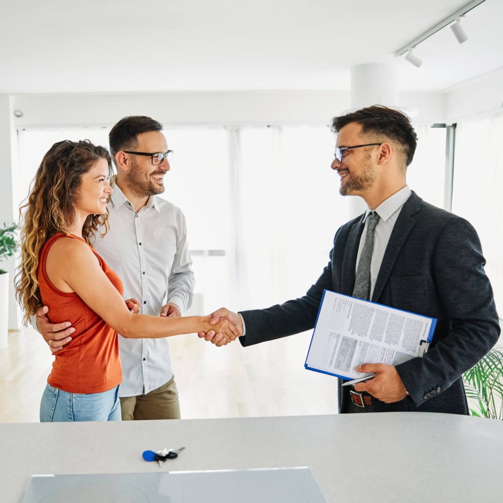 Couple shaking hands with real estate agent.