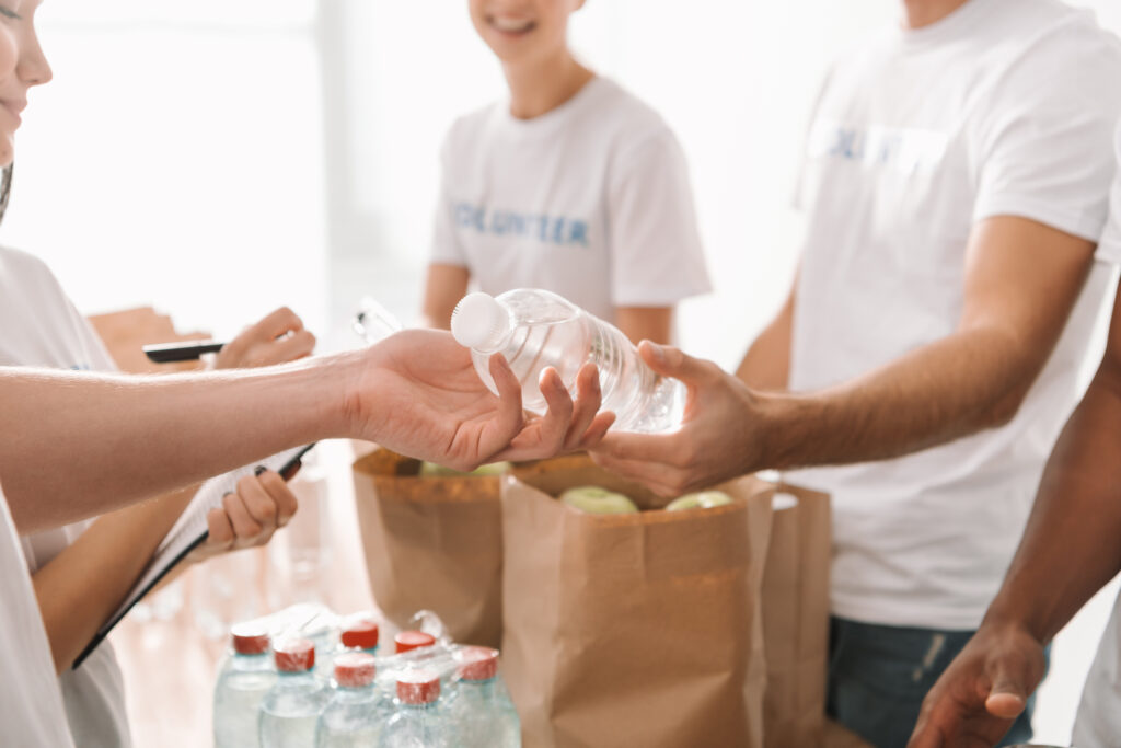 cropped shot of volunteers handing out water bottles and food for charity