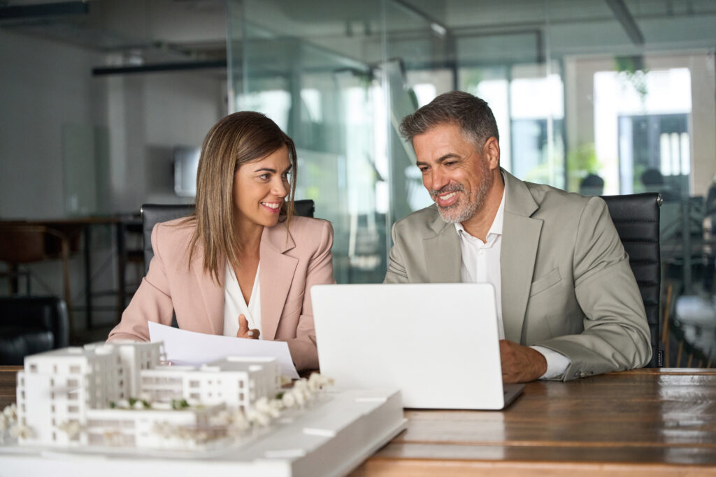 Real estate developers working on laptop discussing new residential or commercial development construction project at meeting.